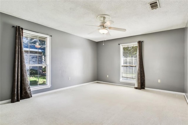 empty room featuring a ceiling fan, carpet, visible vents, and baseboards