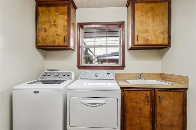 clothes washing area with cabinet space, a sink, and separate washer and dryer