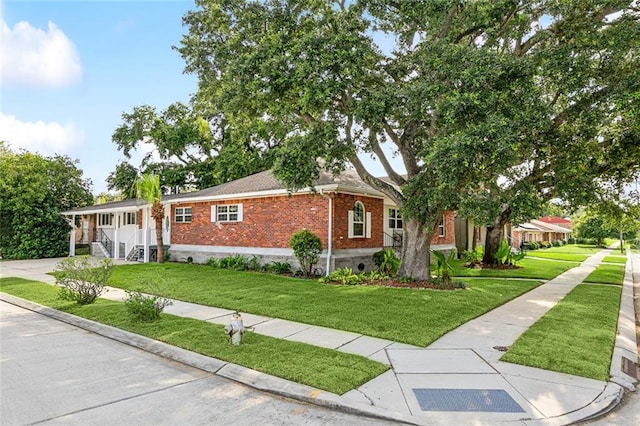 ranch-style house featuring concrete driveway, brick siding, and a front yard