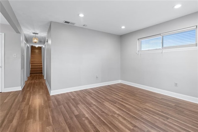 spare room with recessed lighting, wood finished floors, visible vents, baseboards, and stairs