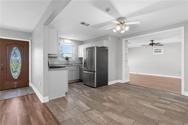 kitchen with light wood-style floors, stainless steel fridge, visible vents, and white cabinetry