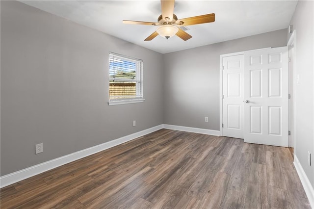 unfurnished bedroom with a ceiling fan, dark wood-style flooring, and baseboards