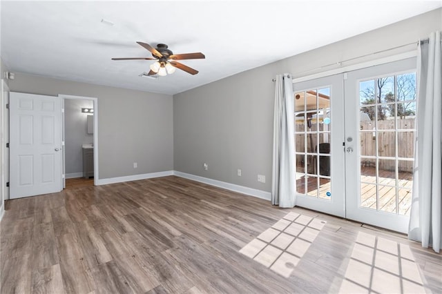 spare room with french doors, wood finished floors, a ceiling fan, and baseboards