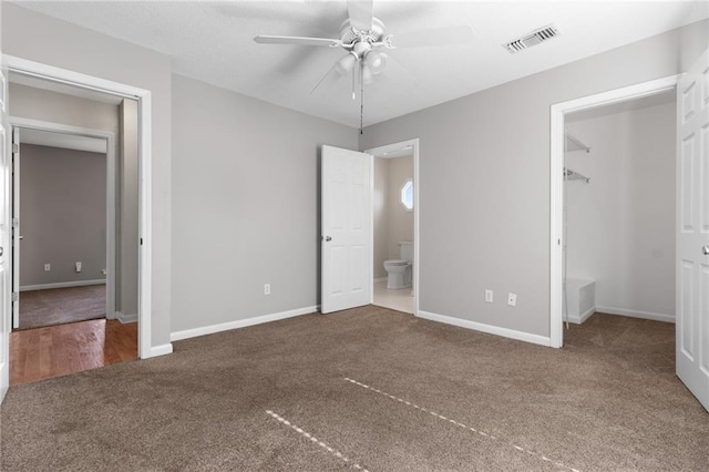 unfurnished bedroom with baseboards, a spacious closet, visible vents, and ensuite bathroom