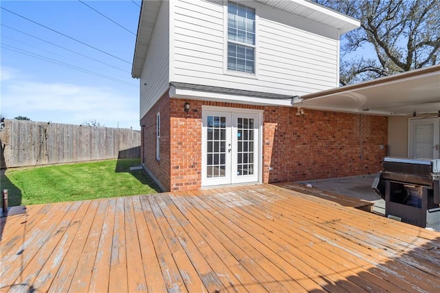 wooden deck with french doors, a lawn, fence, and a grill