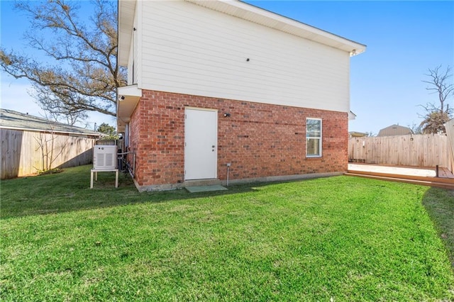 rear view of house with a fenced backyard, a lawn, and brick siding