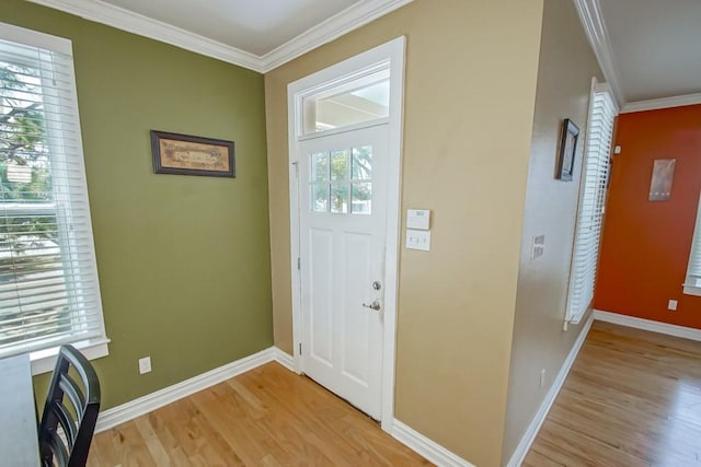 foyer entrance with ornamental molding, light wood-style flooring, and baseboards