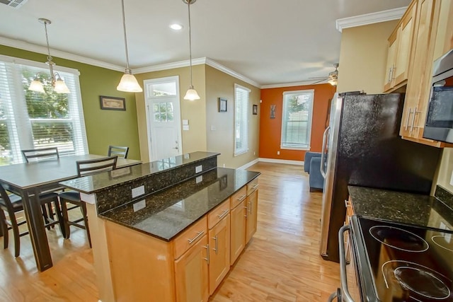 kitchen featuring ornamental molding, a center island, plenty of natural light, and light wood-style flooring