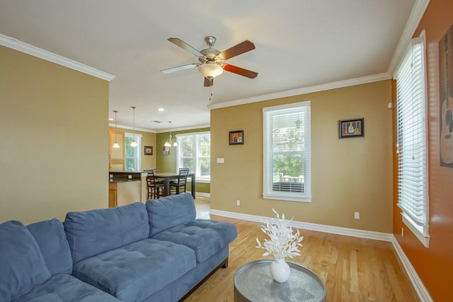 living room featuring light wood-type flooring, baseboards, ornamental molding, and a ceiling fan