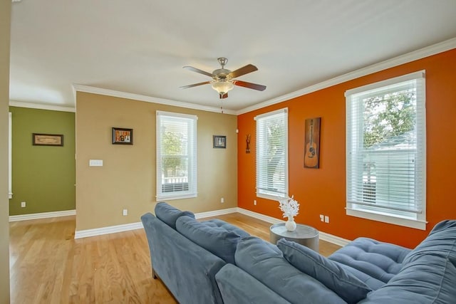 living area with ornamental molding, light wood-type flooring, ceiling fan, and baseboards