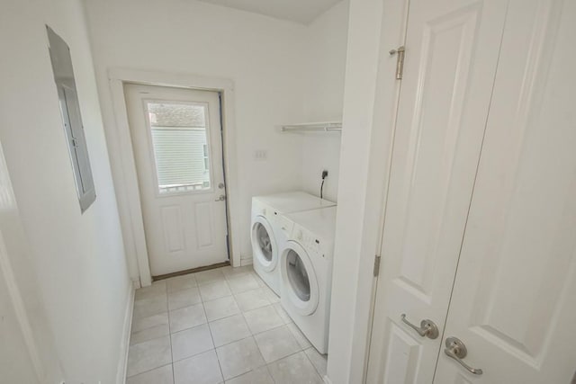 clothes washing area with light tile patterned floors, laundry area, separate washer and dryer, and baseboards