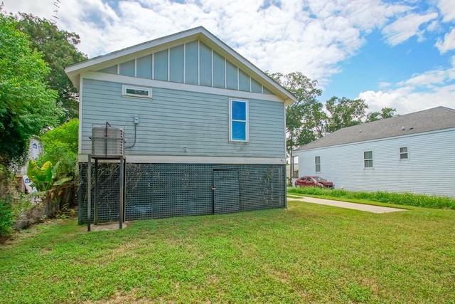 rear view of house with board and batten siding and a yard