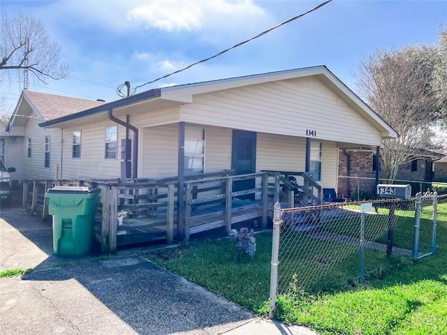 view of front of house featuring driveway, a porch, roof with shingles, fence, and a front lawn