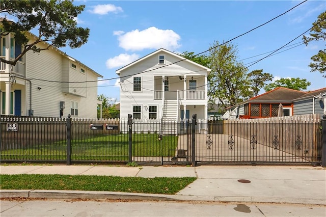 view of front of property with a fenced front yard, a front yard, a gate, and a balcony