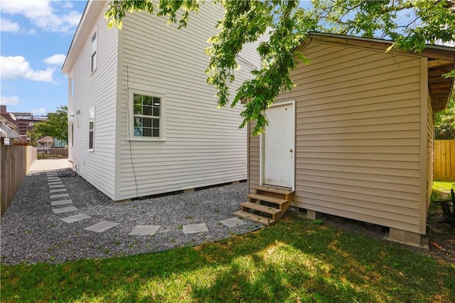 rear view of property with entry steps, a lawn, and fence