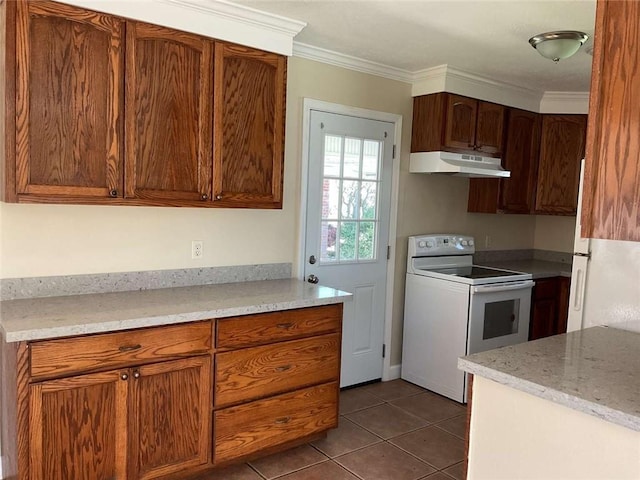 kitchen with under cabinet range hood, white appliances, dark tile patterned floors, ornamental molding, and brown cabinets