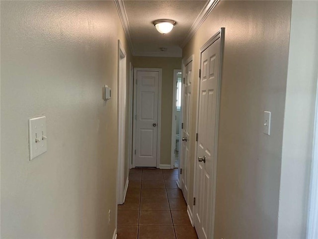 hall with ornamental molding, tile patterned flooring, a textured ceiling, and baseboards