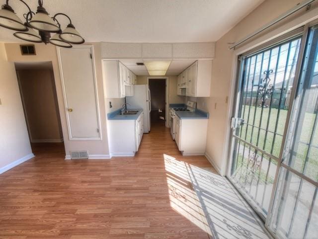 kitchen featuring white appliances, visible vents, light wood-style flooring, and white cabinets