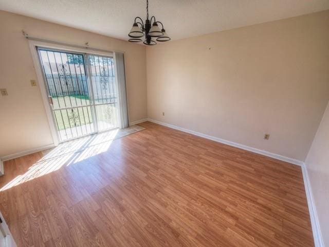 unfurnished room featuring light wood-type flooring, baseboards, and a chandelier