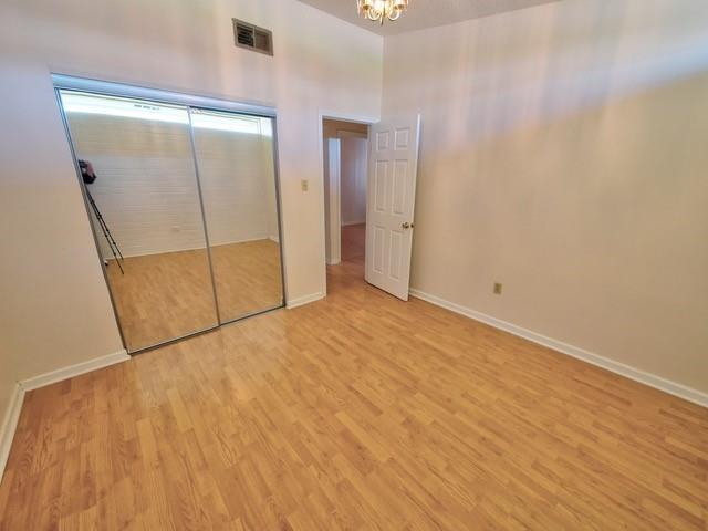 unfurnished bedroom featuring light wood finished floors, baseboards, visible vents, and a closet