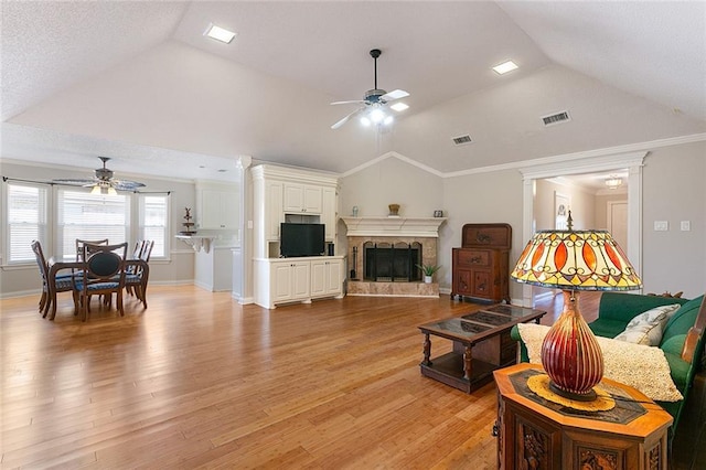 living area with vaulted ceiling, light wood-type flooring, visible vents, and a ceiling fan