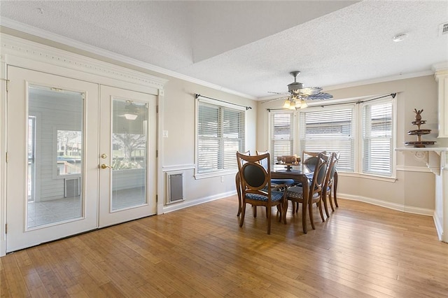 dining area with french doors, light wood finished floors, a wealth of natural light, and crown molding