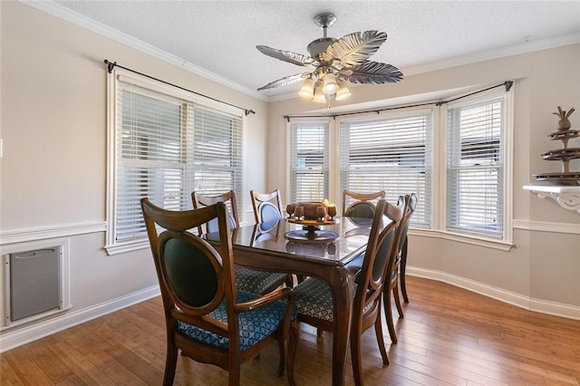 dining area featuring light wood-style floors, a healthy amount of sunlight, ornamental molding, and a textured ceiling