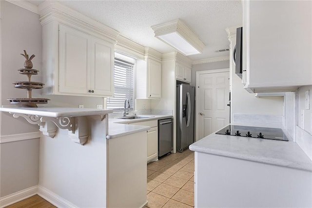 kitchen featuring a breakfast bar area, stainless steel appliances, white cabinetry, a sink, and a peninsula