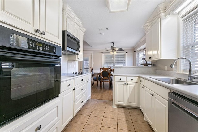 kitchen with black appliances, white cabinets, a sink, and light tile patterned flooring