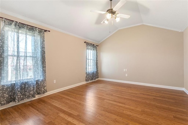 empty room with crown molding, vaulted ceiling, ceiling fan, baseboards, and hardwood / wood-style flooring