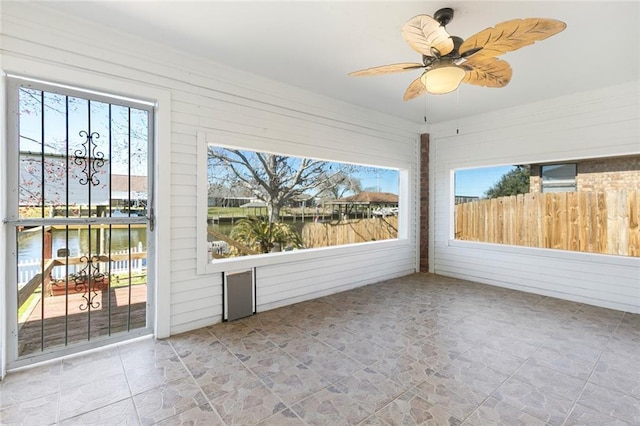 unfurnished sunroom featuring a ceiling fan and a wealth of natural light