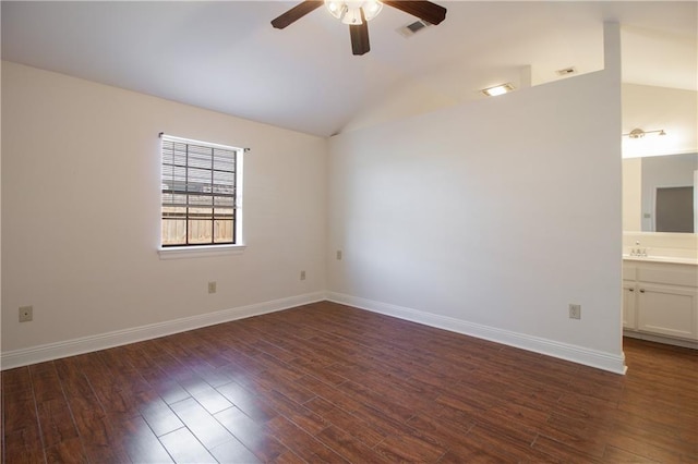 spare room with lofted ceiling, ceiling fan, dark wood-type flooring, visible vents, and baseboards