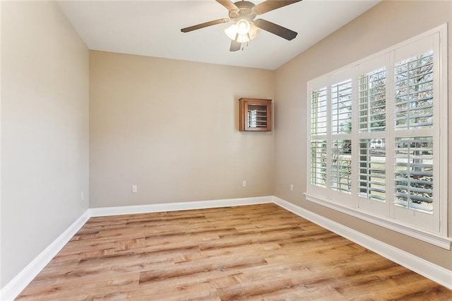 empty room with wood finished floors, a ceiling fan, and baseboards