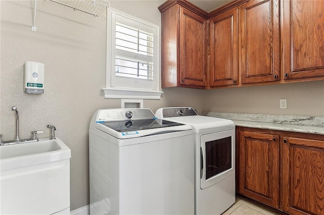 washroom featuring washing machine and dryer, cabinet space, a sink, and light tile patterned floors