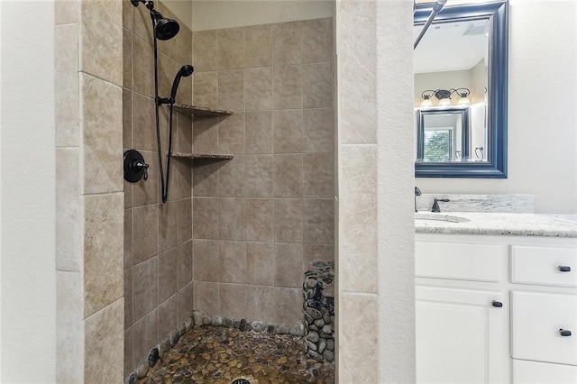 full bathroom with tiled shower and vanity