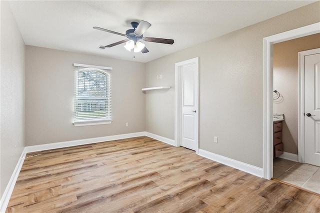 unfurnished bedroom featuring ceiling fan, wood finished floors, connected bathroom, and baseboards