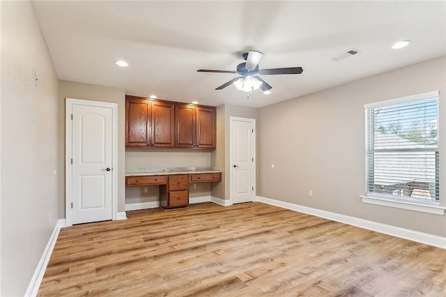 kitchen with visible vents, baseboards, light wood-type flooring, brown cabinets, and built in desk