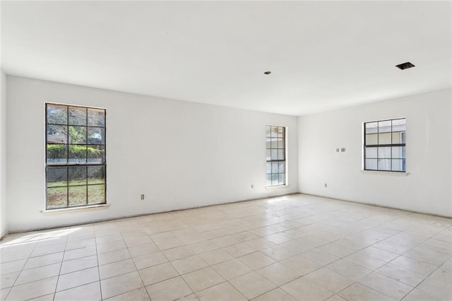 empty room with light tile patterned floors and a wealth of natural light