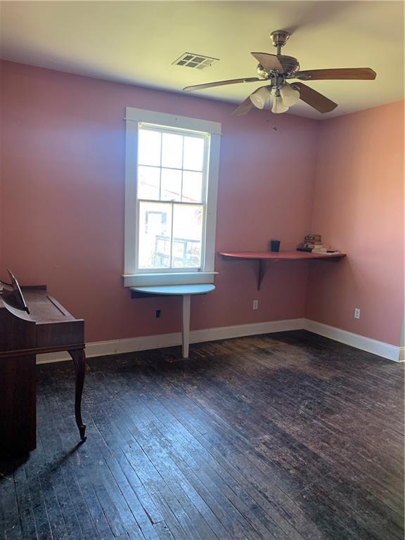 spare room featuring a ceiling fan, baseboards, visible vents, and hardwood / wood-style floors