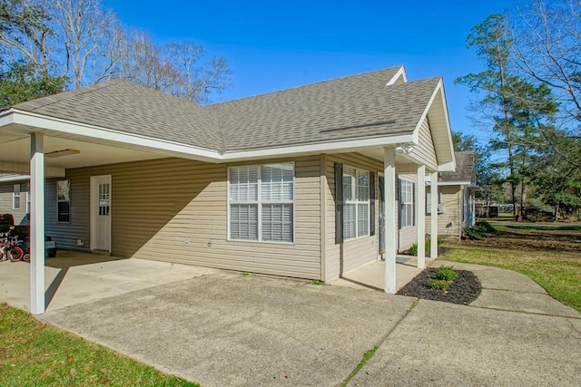 view of side of property with a shingled roof and a carport