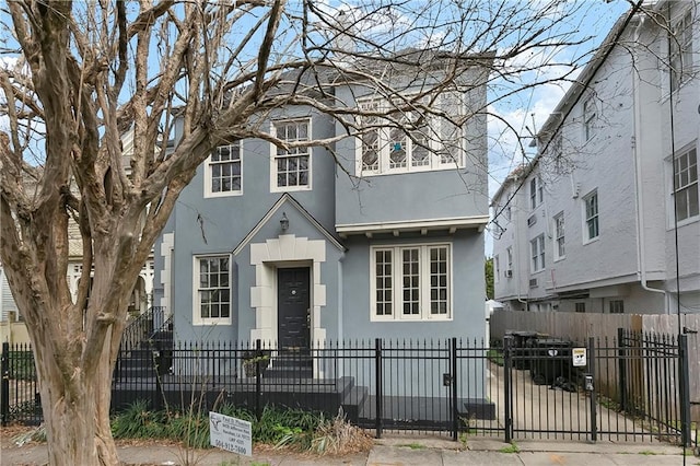 view of front of home with a fenced front yard, a gate, and stucco siding