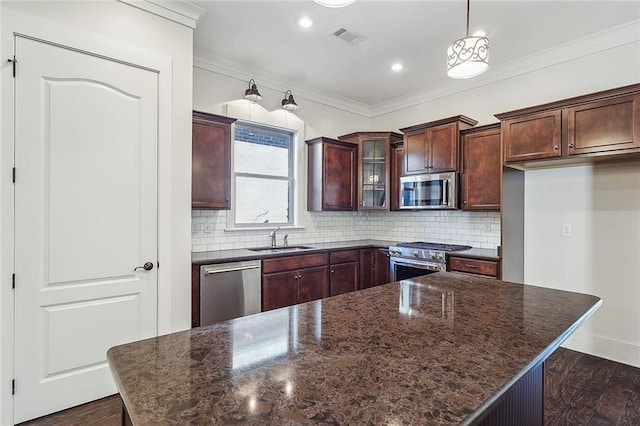 kitchen with stainless steel appliances, visible vents, decorative backsplash, ornamental molding, and a sink