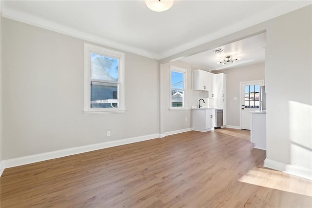 interior space with baseboards, a sink, visible vents, and light wood-style floors