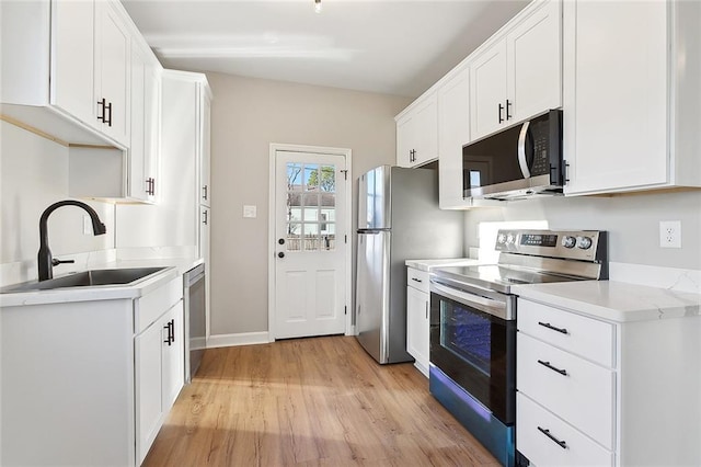 kitchen featuring white cabinetry, appliances with stainless steel finishes, light countertops, and a sink