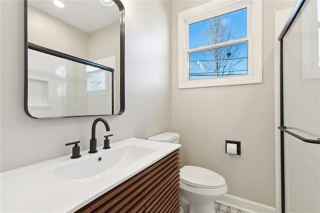 bathroom featuring baseboards, a tile shower, vanity, and toilet