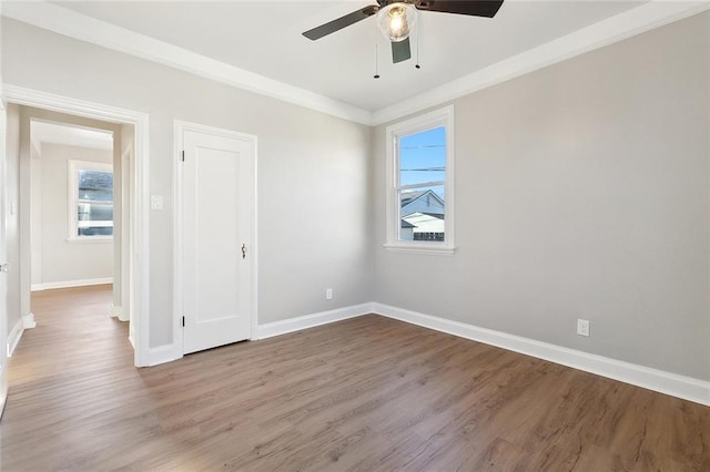 unfurnished room with plenty of natural light, crown molding, baseboards, and wood finished floors