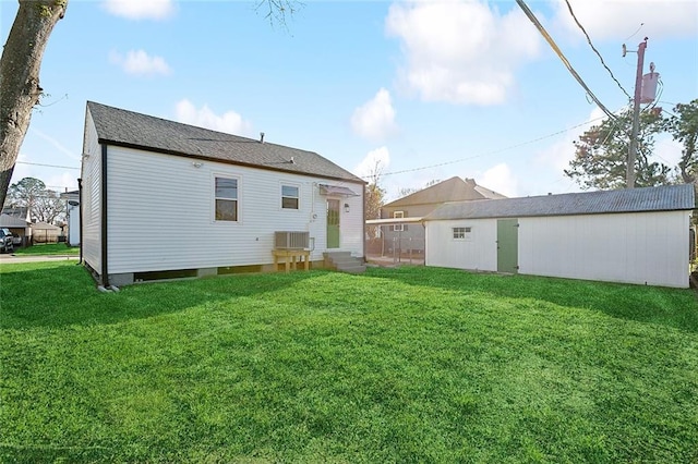 rear view of property featuring entry steps, roof with shingles, a lawn, and central AC unit