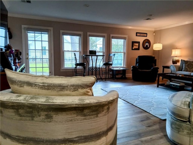 living area with plenty of natural light, visible vents, crown molding, and hardwood / wood-style floors