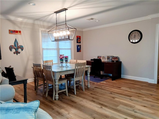 dining area featuring ornamental molding, light wood-type flooring, visible vents, and baseboards