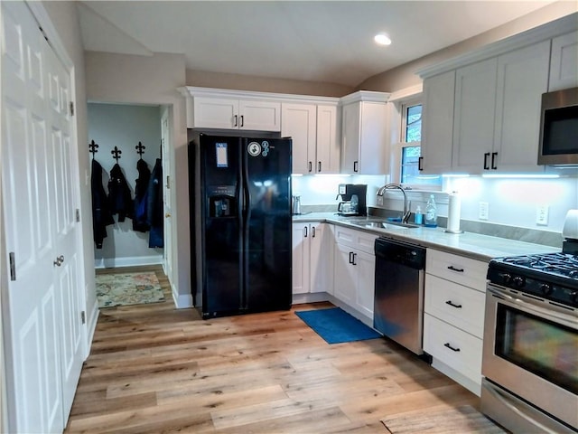 kitchen featuring a sink, white cabinetry, light wood-style floors, light countertops, and appliances with stainless steel finishes